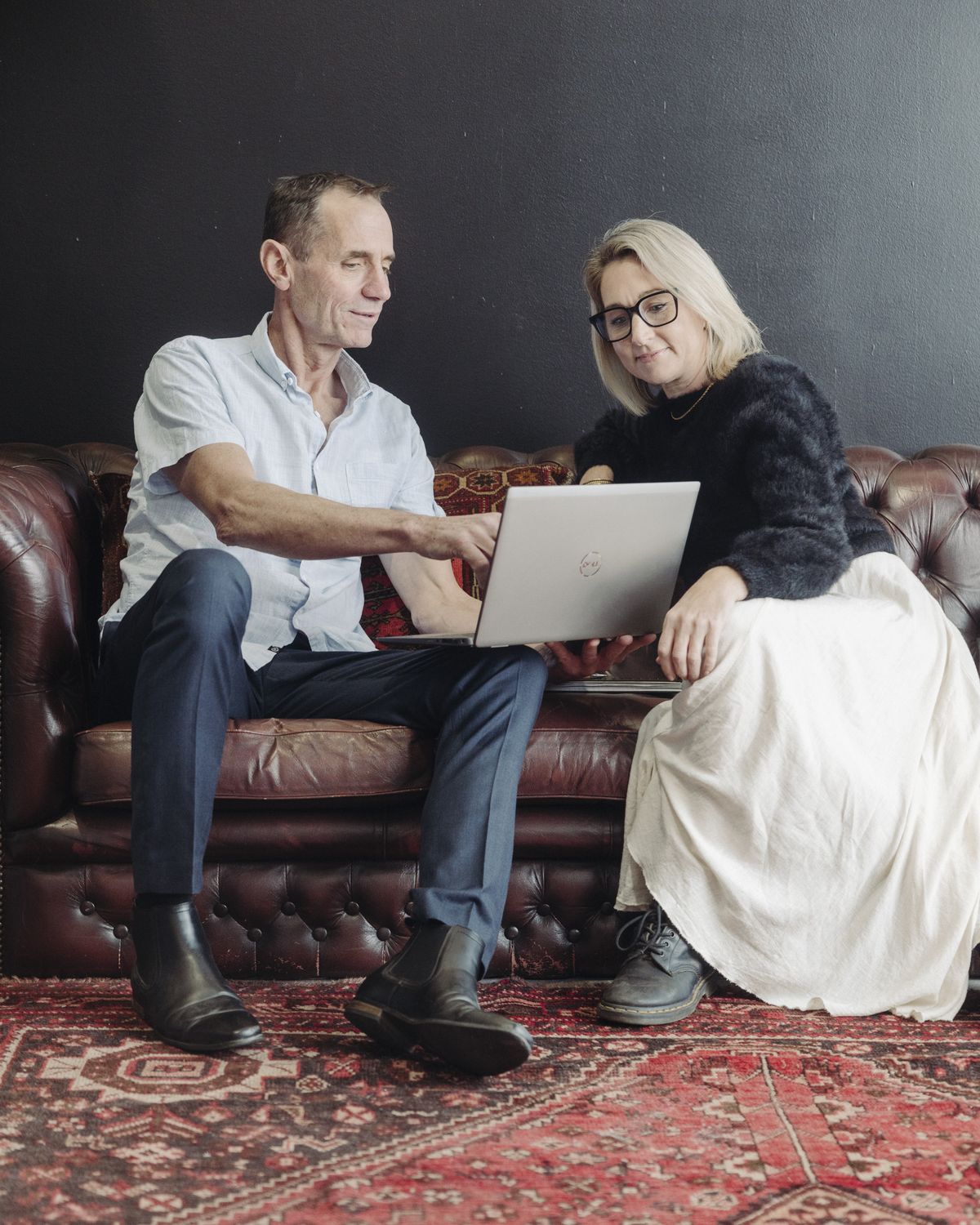 Mike working through a laptop with a client on a leather couch